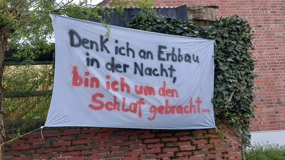 Ein Protest-Plakat hängt vor einem Haus.