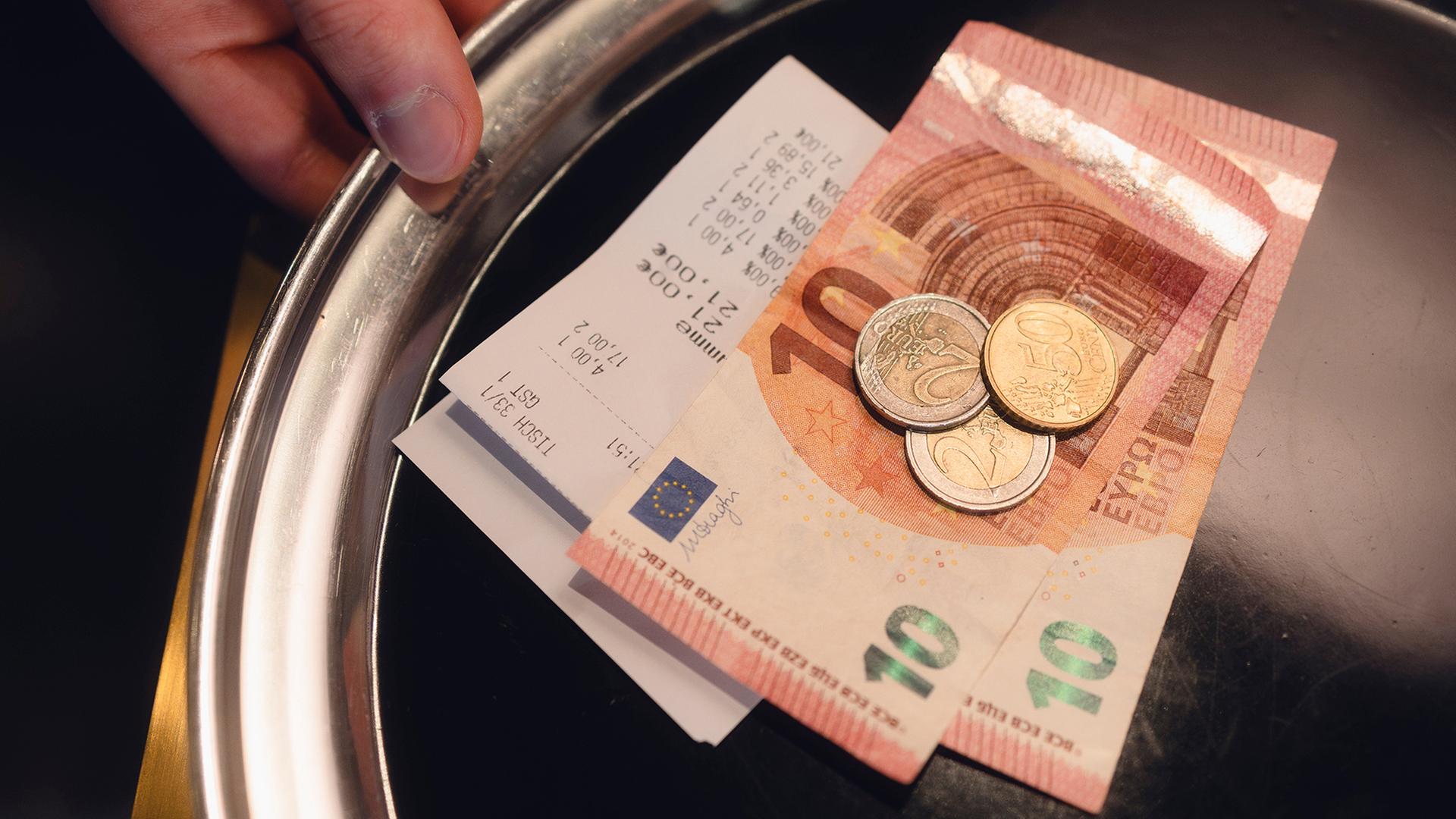 Ein silbernes Kelnertablett auf dem eine Rechnung und Bargeld liegt | AdobeStock/Medienzunft Berlin