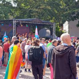 Menschen stehen beim CSD Burgdorf vor einer Bühne.