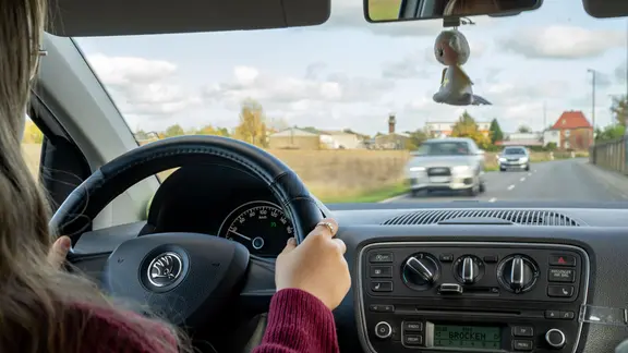 Eine junge Fahranfängerin sitzt hinter dem Steuer eines Autos.