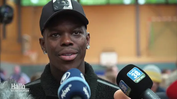 Basketball world champion Dennis Schröder gives an interview in a gym.