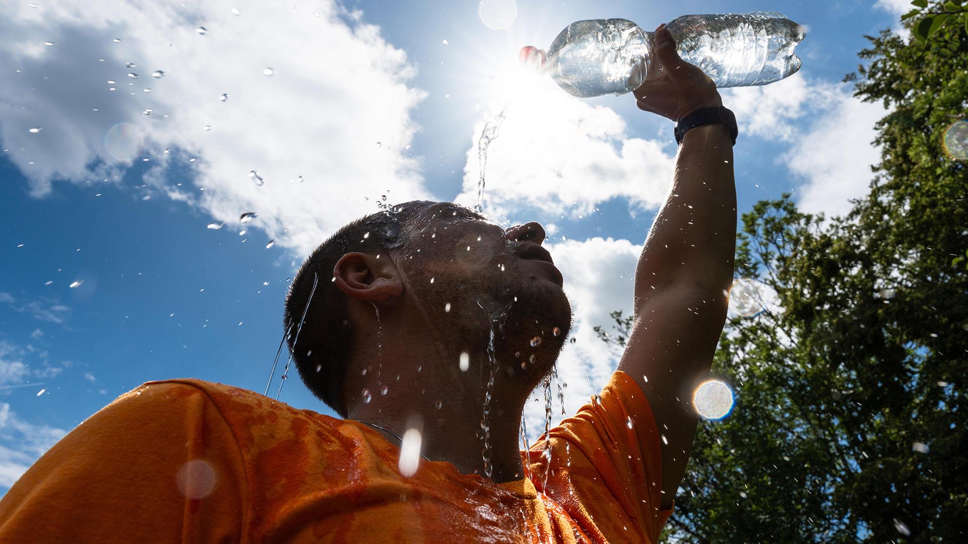 Mann kühlt sich bei sommerlicher Hitze mit Wasser ab | picture alliance / CHROMORANGE / Michael Bihlmayer