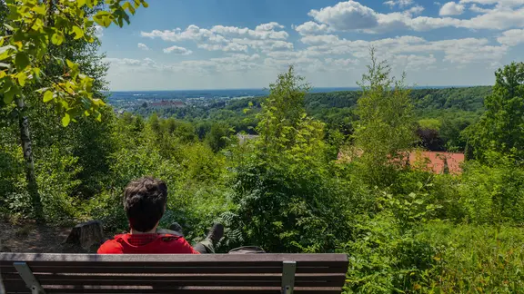Ein Wanderer macht Rast auf einer Bank am Ahornweg im Osnabrücker Land.