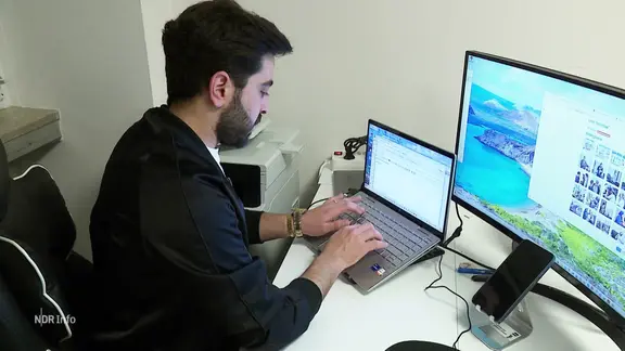 Ein Mann arbeitet an zwei Bildschirmen.