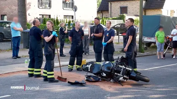 Einsatzkräfte stehen neben einem verunglückten Motorrad.