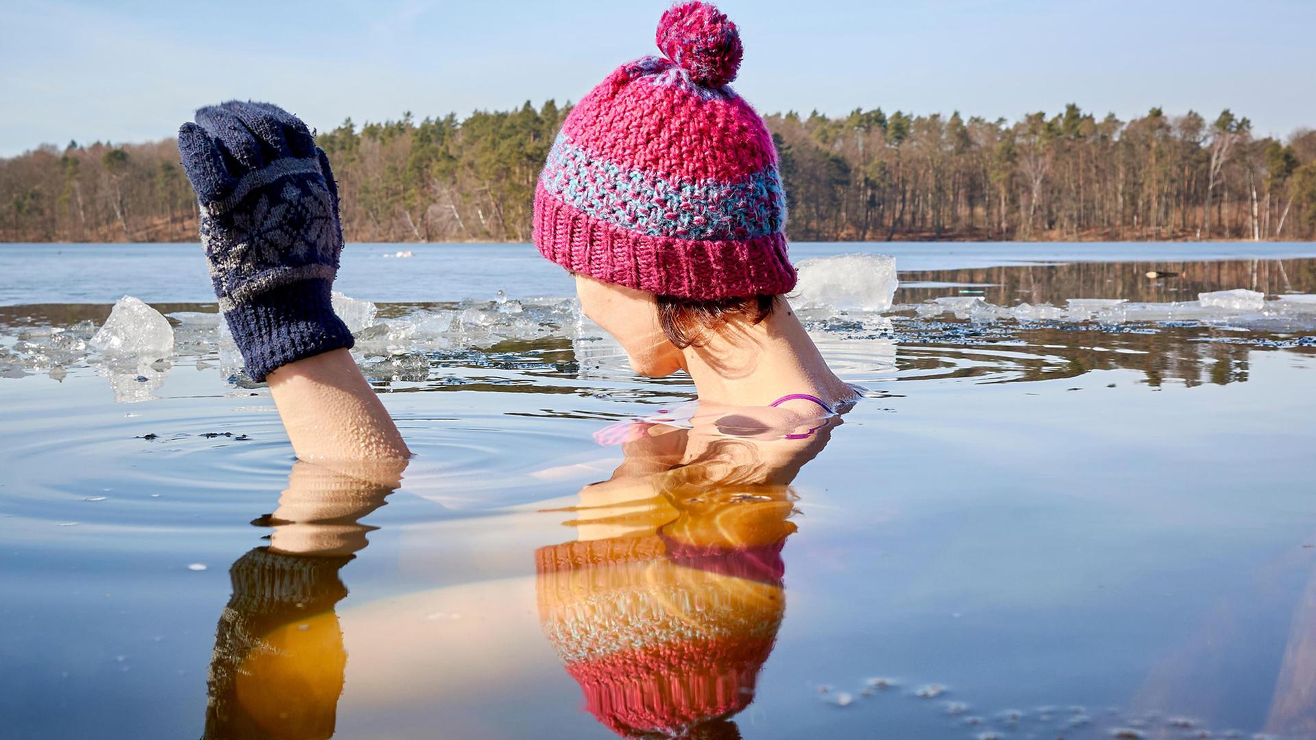 Eine Frau mit Wollmütze und Wollhandschuhen beim Eisbaden. | Colourbox, -