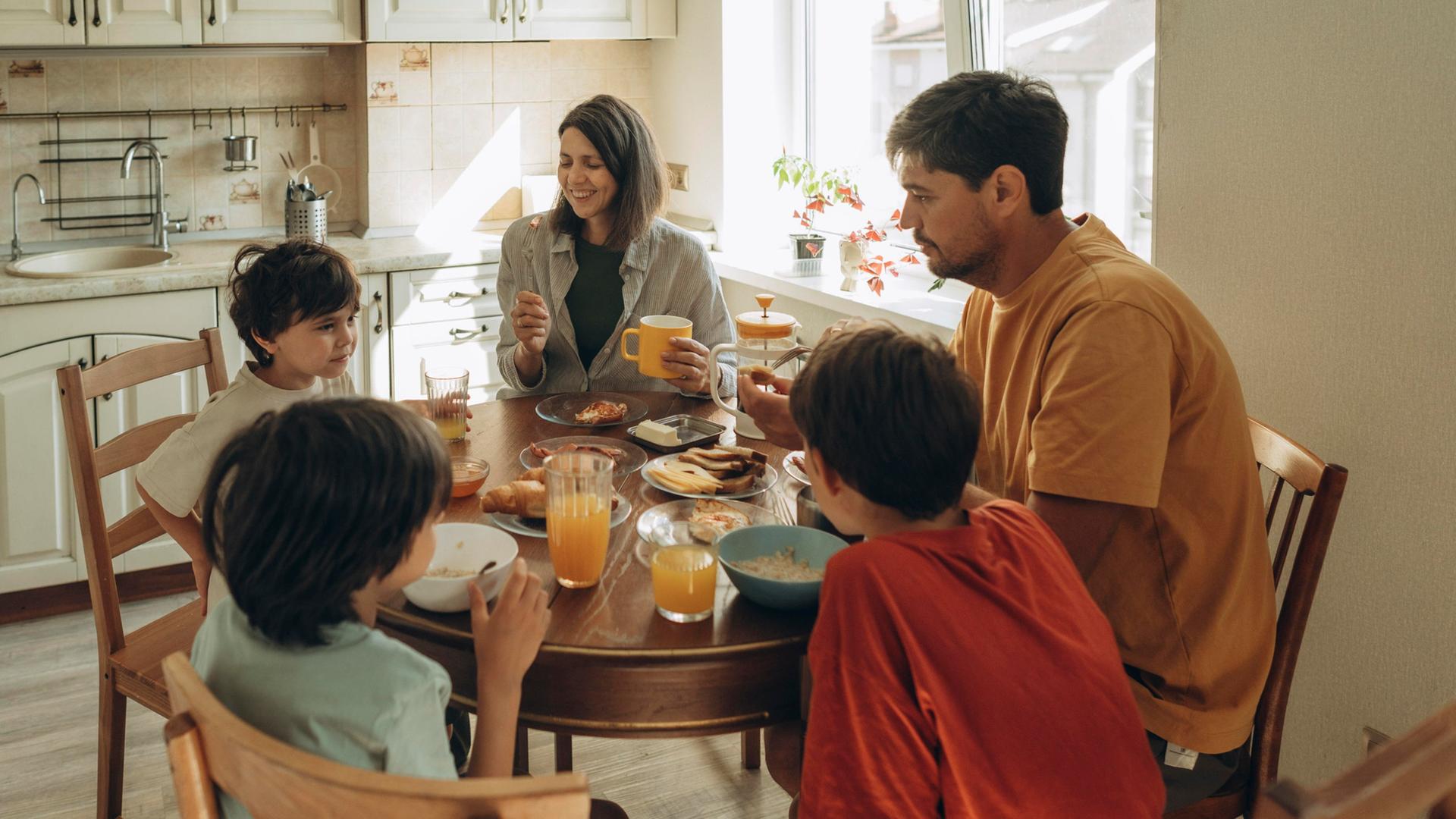 Eine Familie nimmt am Esstisch eine Mahlzeit zu sich. | picture alliance / Westend61 | Anastasiya Amraeva