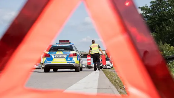 Ein Polizist sichert eine Unfallstelle auf einer Autobahn.
