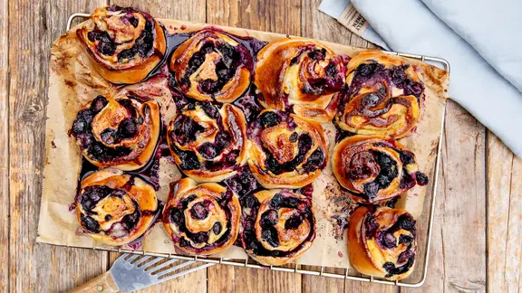 Hefeschnecken mit Blaubeerfüllung auf einem Kuchengitter.