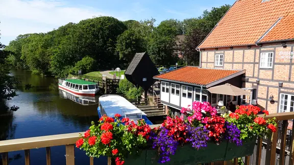 Blick von einer Brücke auf die Medem in Otterndorf mit Ausflugsschiffen.