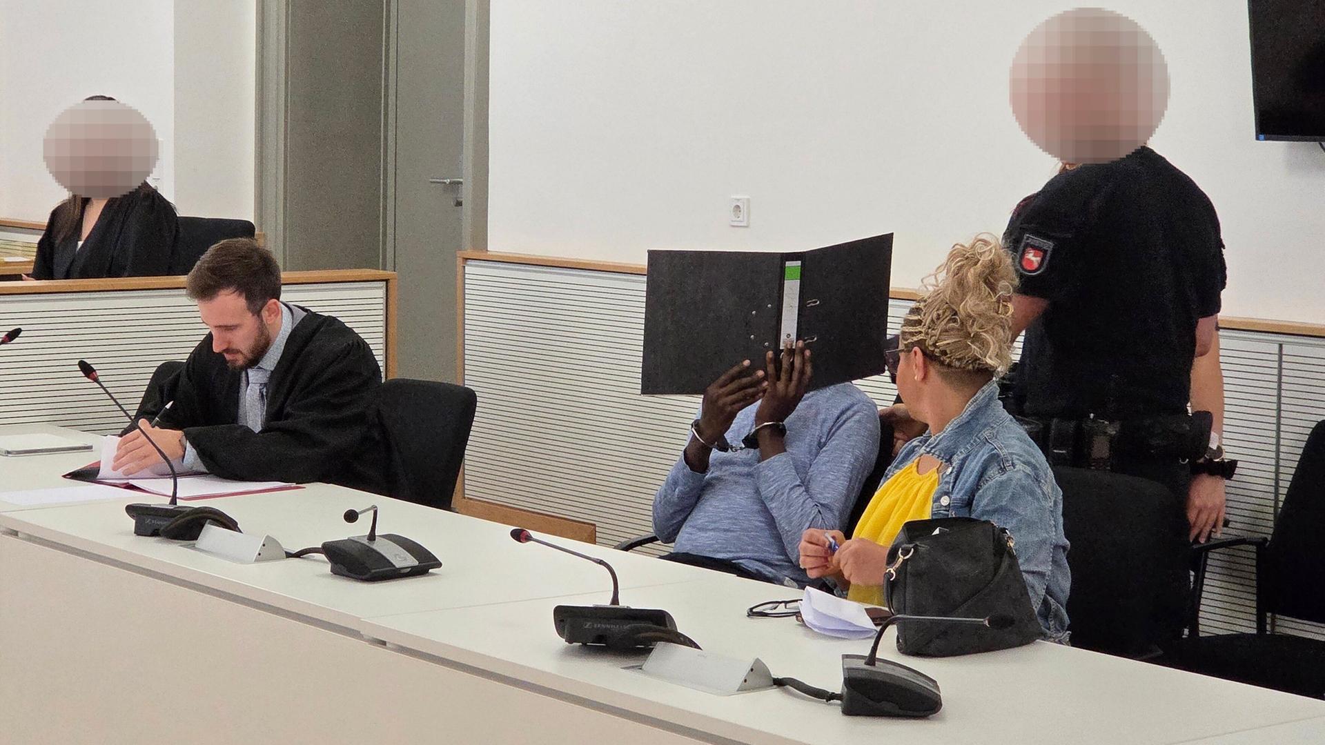 Der Angeklagte sitzt im Gericht neben seinem Verteidiger (l.) und der Dolmetscherin. | picture alliance/dpa, Christian Brahmann