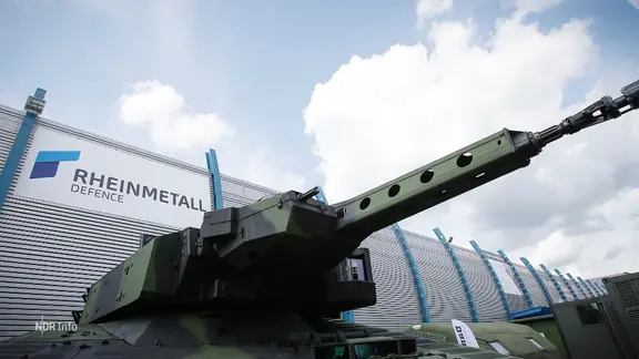 Ein Panzer steht vor einer Rheinmetall-Fabrikhalle.