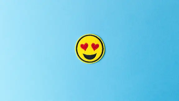 Ein Emoji mit Herzchen-Augen auf hellblauem Hintergrund.