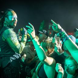 Ein Musiker von The Prodigy steht mitten im feiernden Publikum, das die Hände in die Höhe reckt und ausgelassen tanzt.