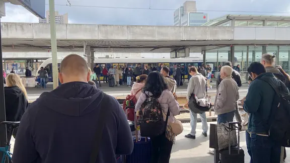 Zahlreiche Menschen stehen im Hauptbahnhof Hannover an den Gleisen.