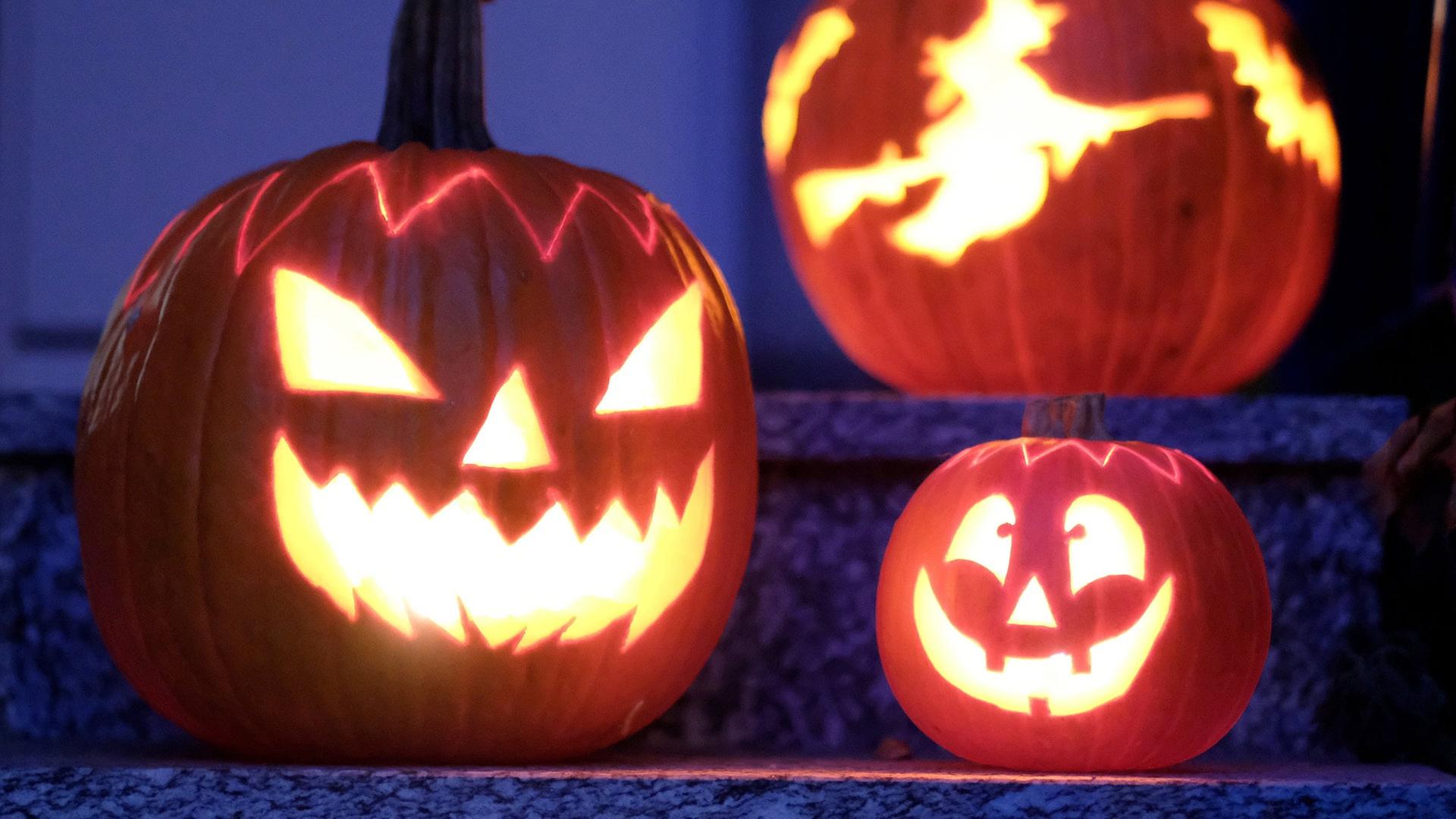 Drei beleuchtete Halloweenkürbisse stehen auf einer Treppe. | picture alliance/dpa | Bernd Weissbrod