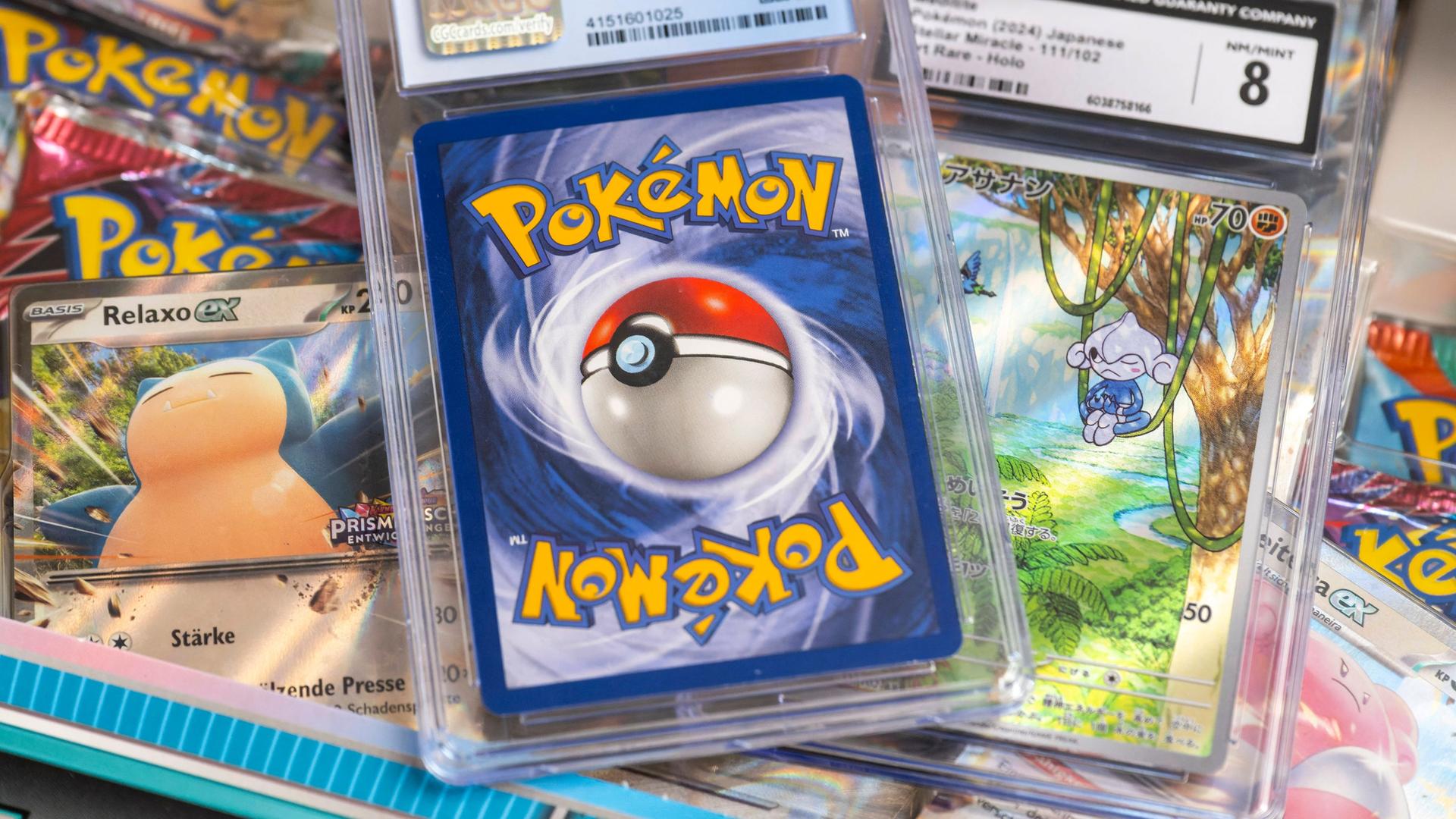 Karten eingeschlagen in Plastik liegen aufeinander, ein Pokemonball ist darauf zu sehen. | IMAGO / MiS