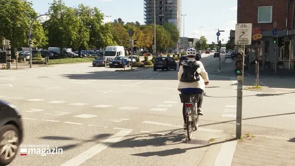 Eine Fahrradfahrerin fährt über eine Straßenkreuzung.