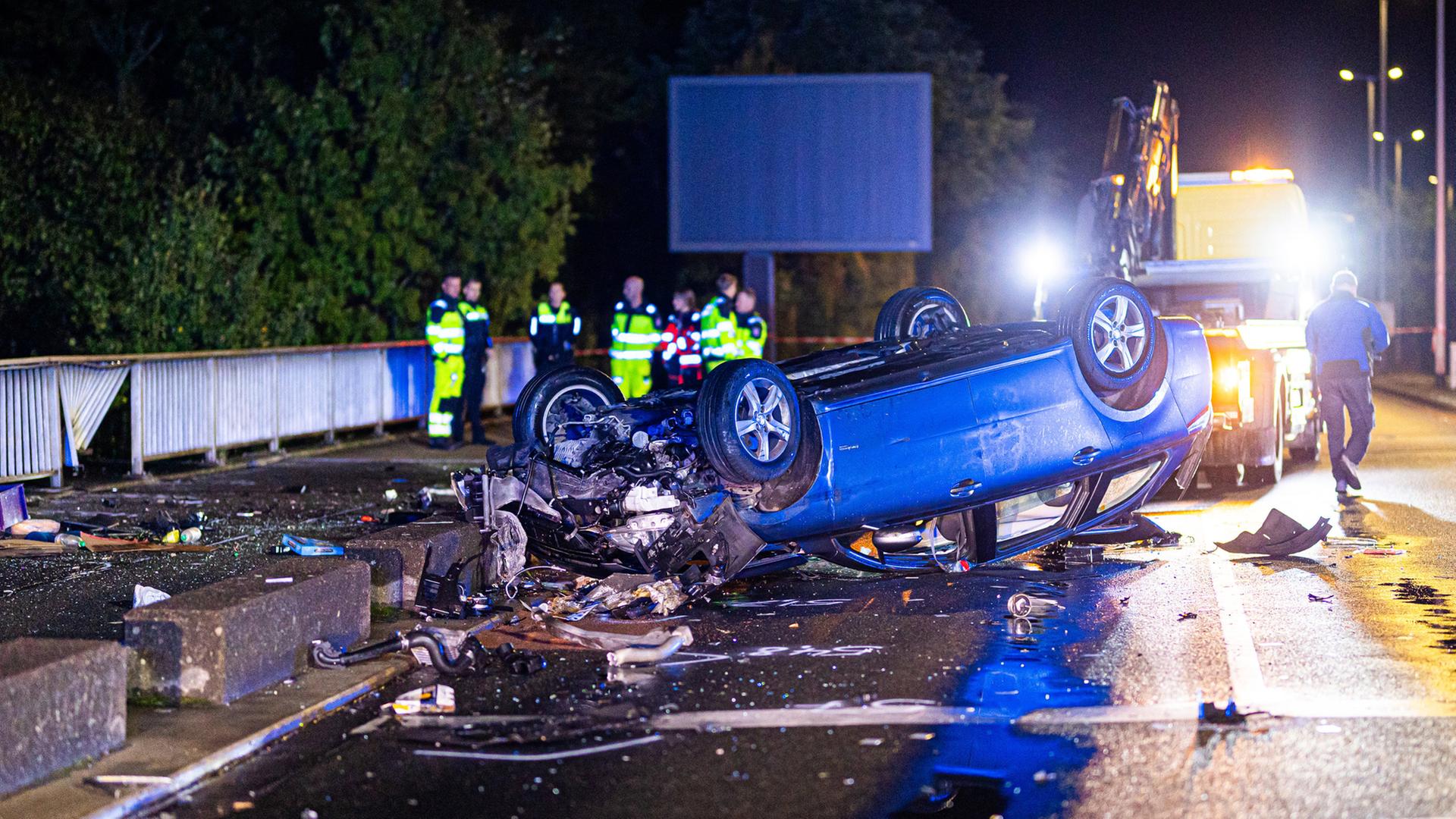 Hannover: Ein verunfalltes Auto liegt auf dem Dach auf einer Brücke hinter Betonbaken.  | Moritz Frankenberg/dpa