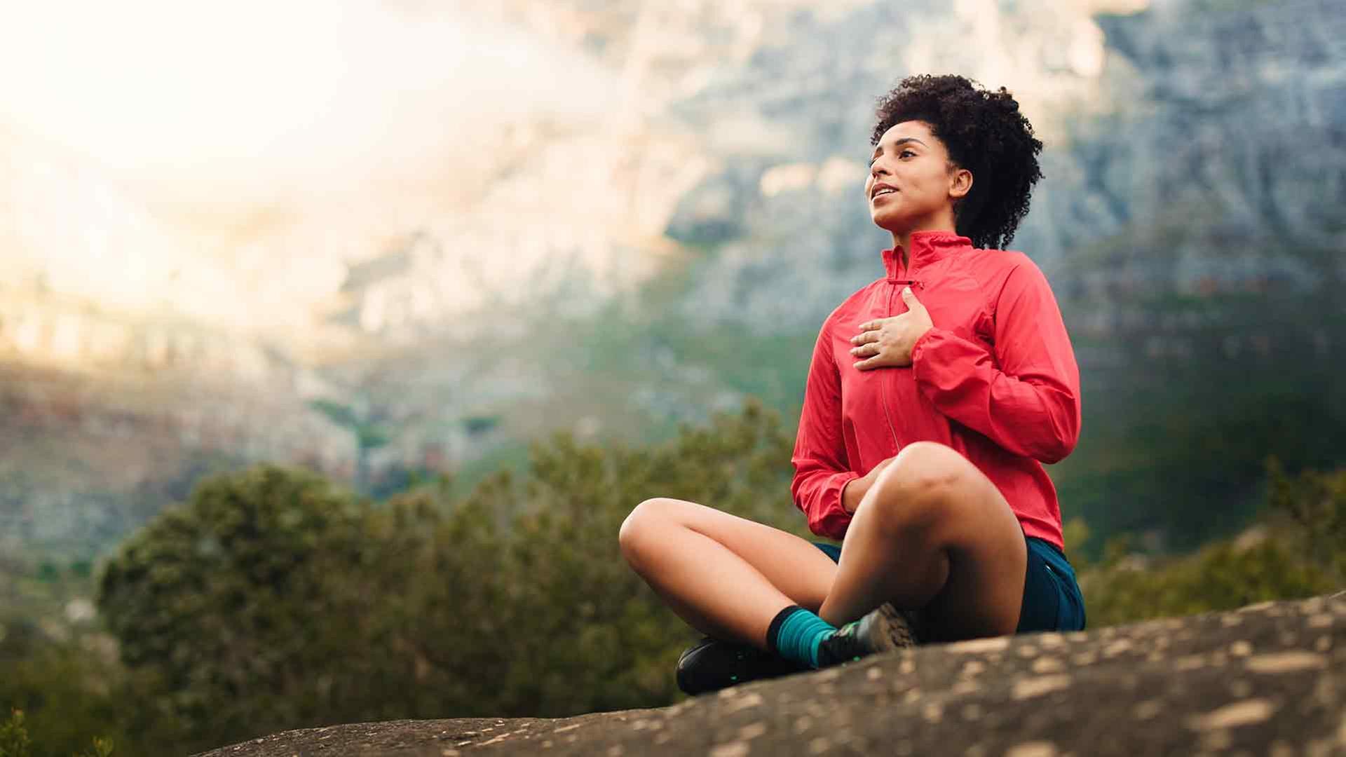 Eine Frau in Sportkleidung meditiert und hat die Hand auf die Brust gelegt | colourbox.de / Peopleimages.com