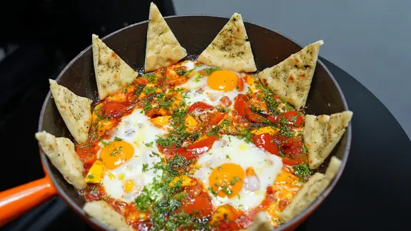 Shakshuka mit Fladenbrot in einer Pfanne serviert