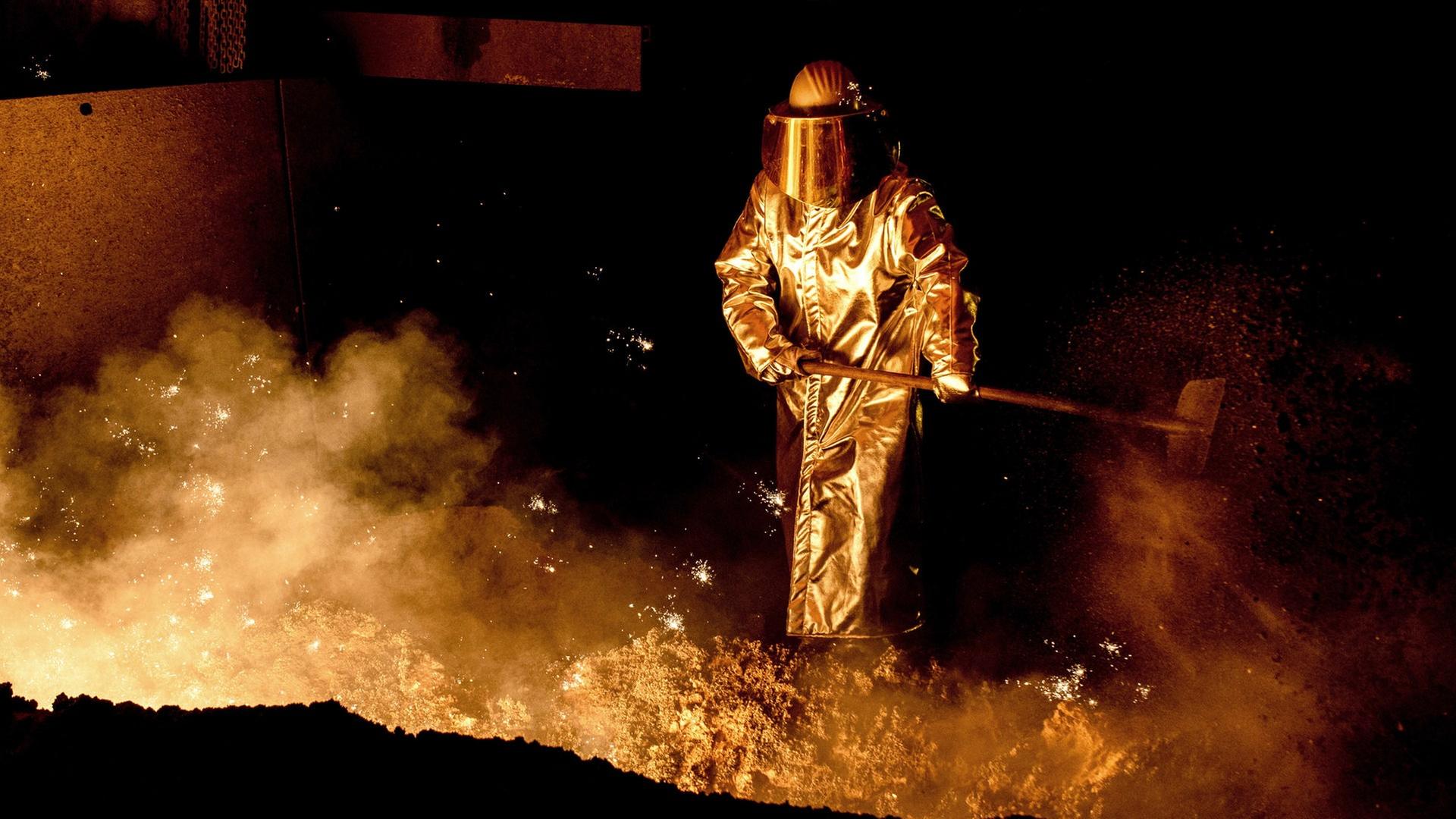 Ein Mitarbeiter schaufelt im Stahlwerk der Salzgitter AG Sand in die Abstichrinne am Hochofen. | picture alliance/dpa, Hauke-Christian Dittrich