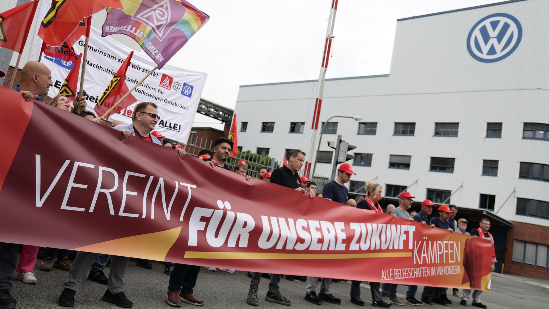 Mitarbeitende von Volkswagen beteiligen sich an einer Informations- und Protestaktion der IG Metall vor dem VW-Werk in Osnabrück. | dpa, David Ebener