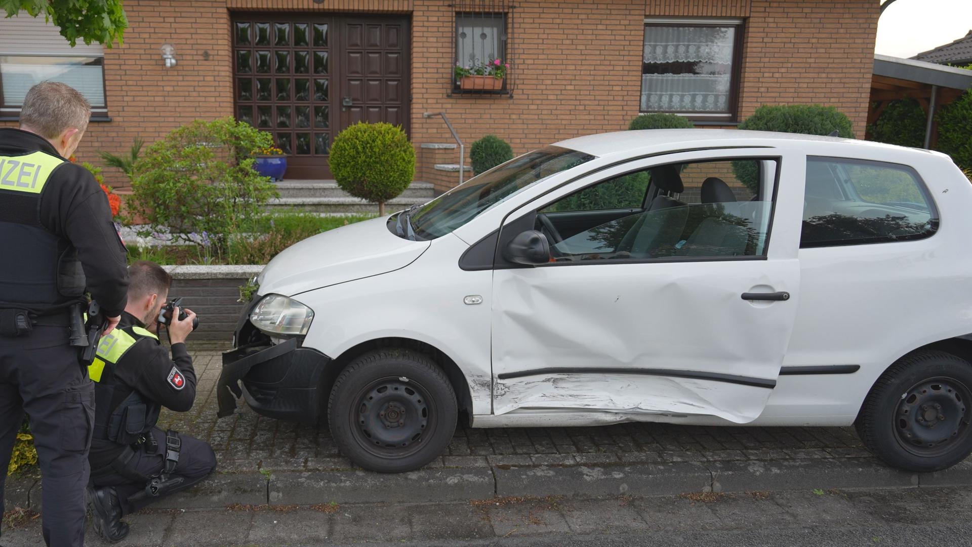 Polizisten stehen vor einem Kleinwagen, geparkt vor einem Haus, und schießen Fotos. | Nord-West-Media TV