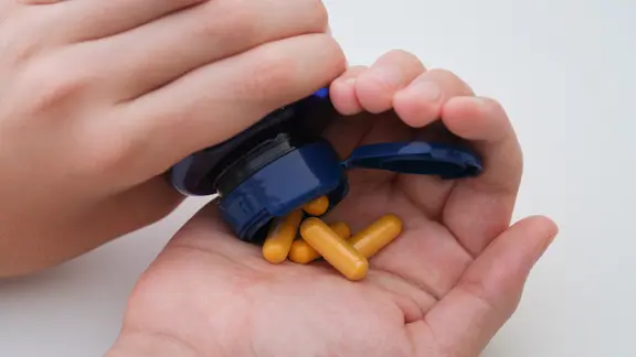 Vitamin B6 Kapseln: Eine Flasche mit Kapseln wird auf einer Hand entleert.