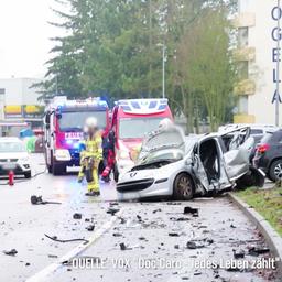 Bei einem schweren Autounfall steht ein komplett verbeulter PKW am Straßenrand einer Straße in einem Wohngebiet, Einsatzkräfte der Feuerwehr sichern die Unfallstelle.