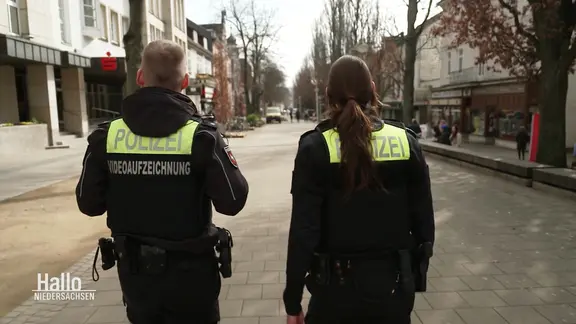 Ein Polizist und eine Polizistin gehen durch eine Einkaufsstraße.