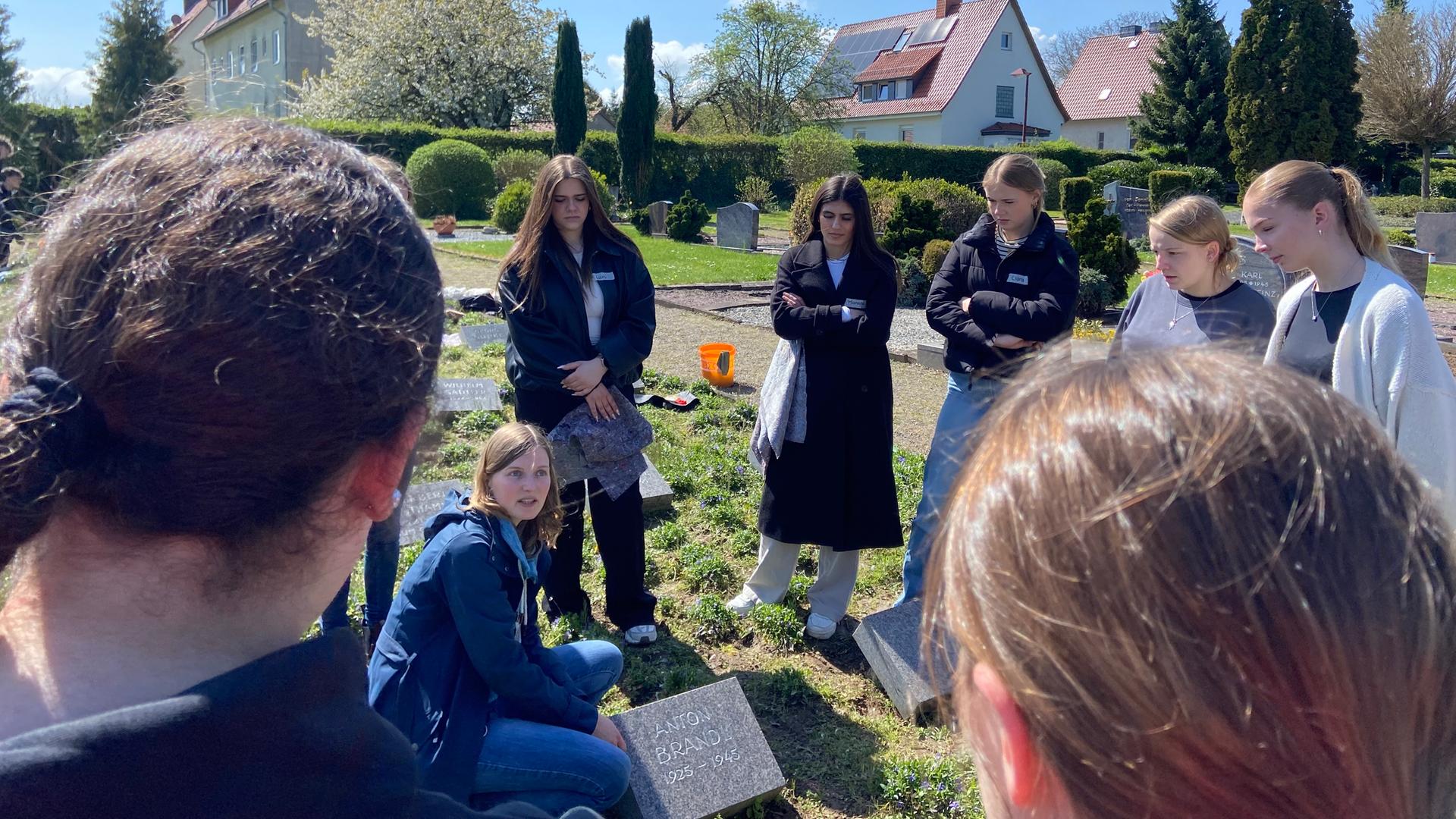 Schülerinnen und Schüler stehen an Grabsteinen von jugendlichen Opfern des KZ Moringen. | NDR / Mara Weißkittel