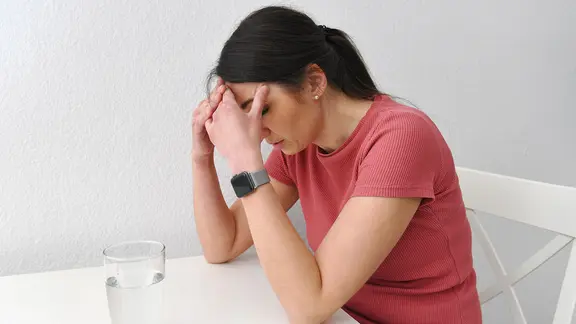 Eine erschöpfte Frau sitzt am Tisch