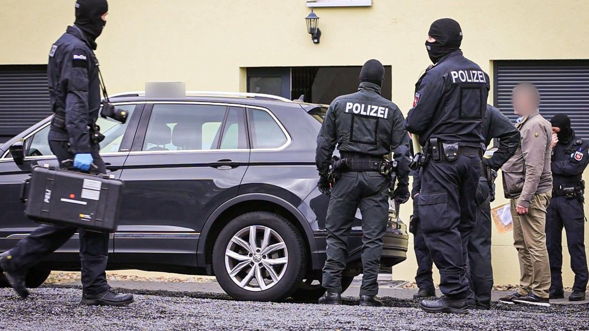 Schwarz gekleidete Polizisten stehen vor einem Haus. | dpa