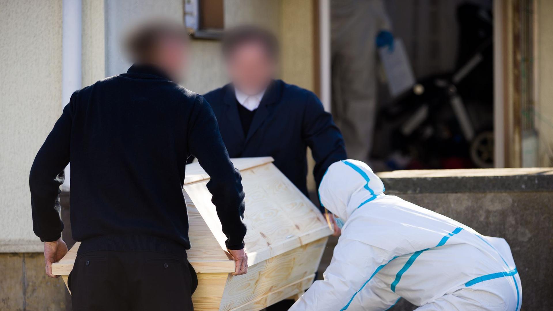 Bestatter verlassen mit einem Sarg ein Einfamilienhaus in der Region Hannover, während Mitarbeiter der Spurensicherung anwesend sind. | Moritz Frankenberg/dpa