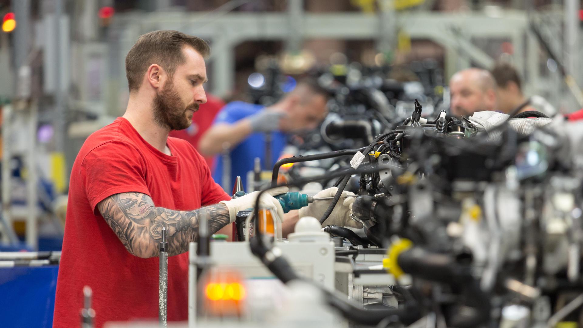 Ein Arbeiter montiert einen Motorblock bei VW | picture alliance / Caro | Bastian
