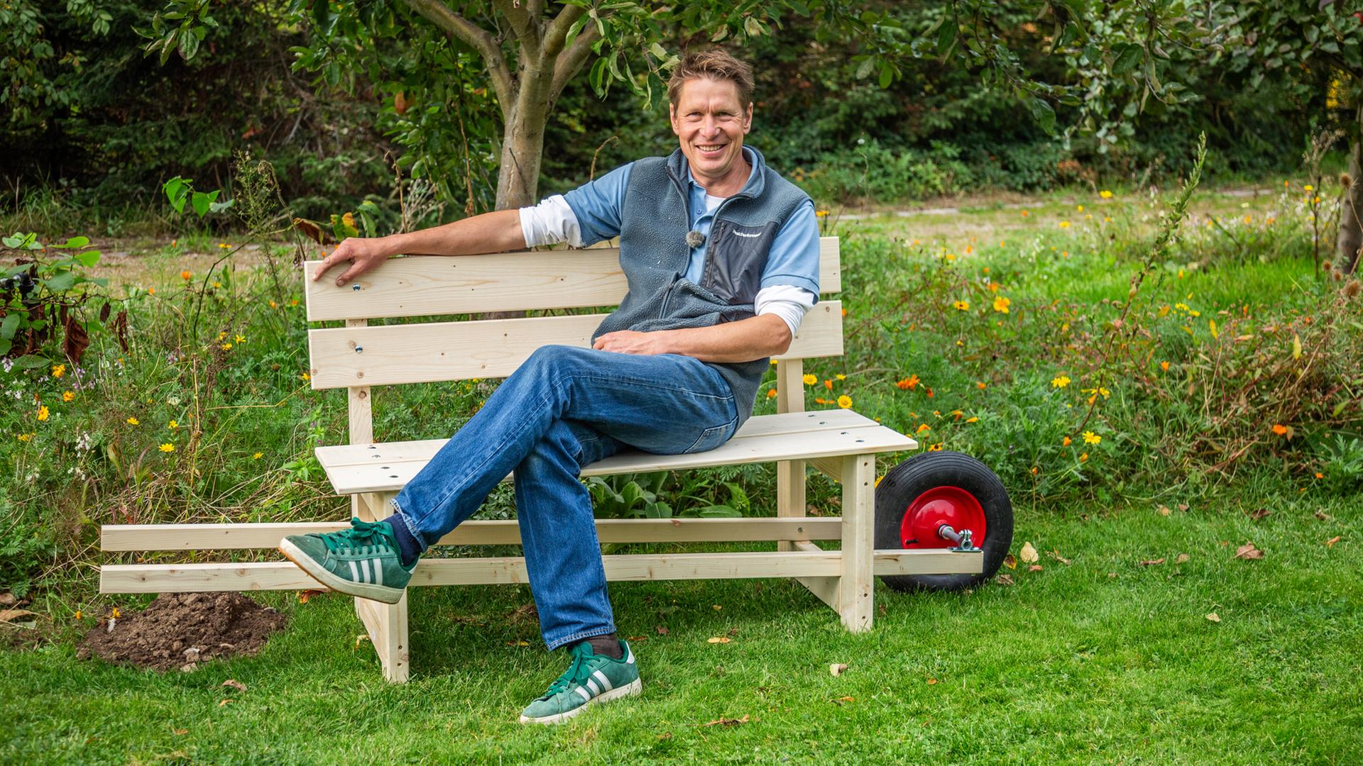 Gärtner Peter Rasch sitzt auf seiner selbst gebauten mobilen Gartenbank | NDR/Udo Tanske