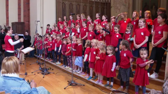 Ein Kinderchor trägt bei einem Auftritt die Farbe Rot.