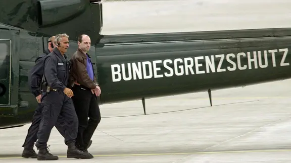 Der Hauptäter der Reemtsma-Entführung 1996, Thomas Drach, wird am 29. Juli 2000 auf dem Hamburger Flughafen von zwei Polizeibeamten begleitet, nachdem er einen Hubschrauber verlassen hat.