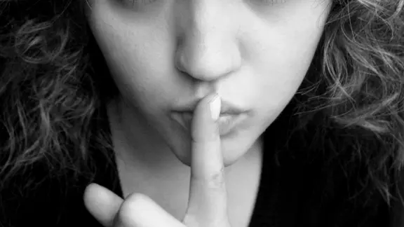 Eine Frau hebt den Zeigefinger an den Mund. | g.sperling / photocase.de, g.sperling / photocase.de Eine Frau hebt den Zeigefinger an den Mund.
