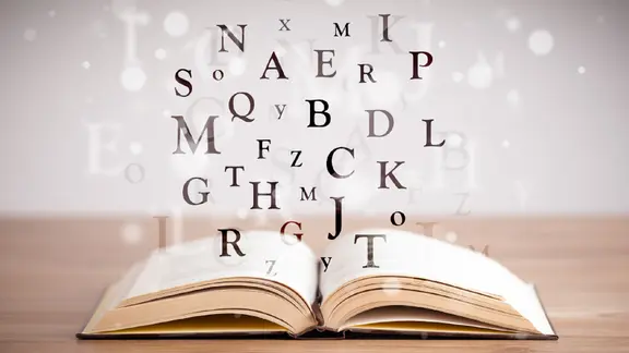 Buchstaben fliegen aus einem offenem Buch.