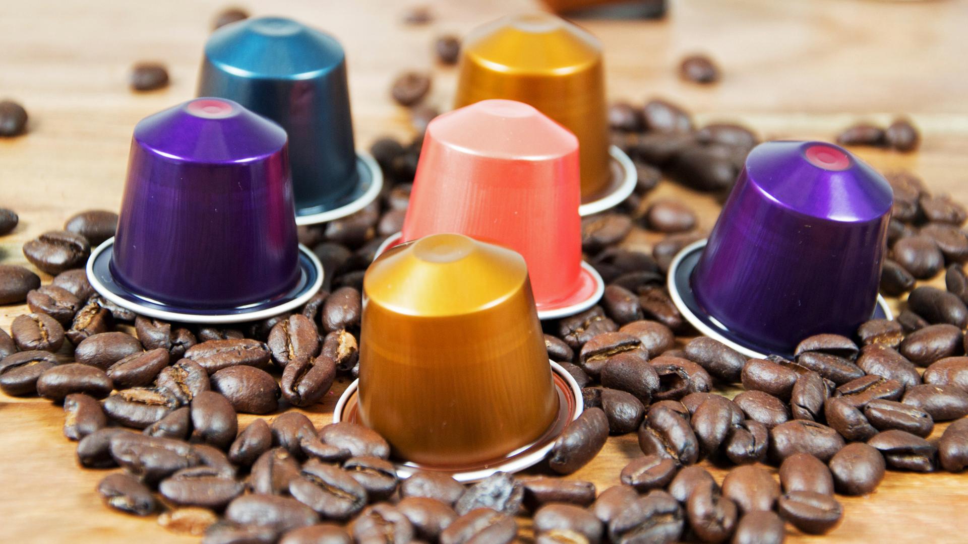 Bunte Kaffeekapseln auf einem Tisch mit Kaffeebohnen | Fotolia, Daniela Stärk