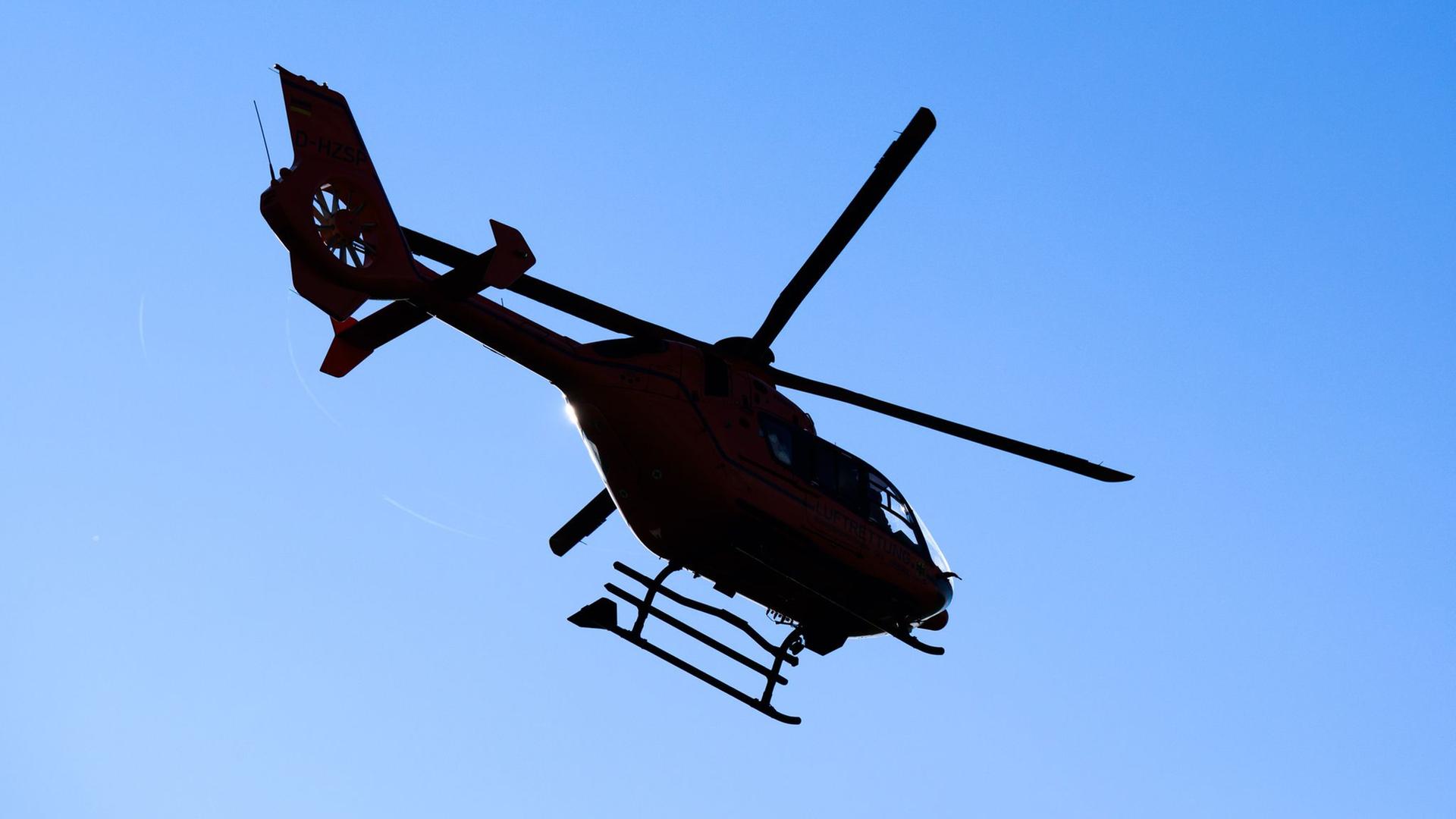 Ein Rettungshubschrauber im Gegenlicht vor blauem Himmel | Julian Stratenschulte/dpa