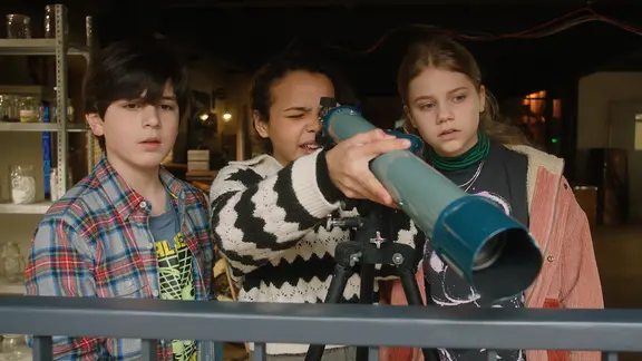 Jules, Taara und Malin beobachten das Nachbarhaus mit dem Fernrohr.