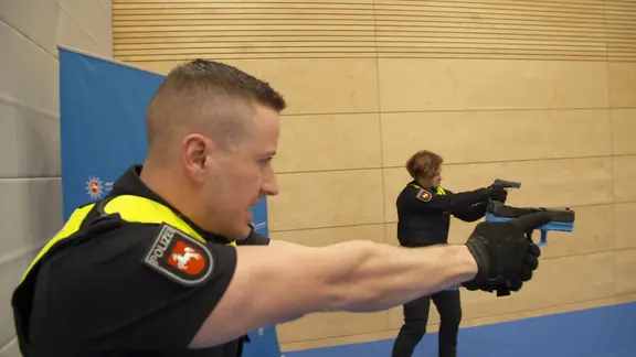 Polizisten zielen beim Training in einer Sporthalle mit ihren Schusswaffen