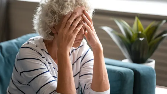 Eine Frau sitzt erschöpft auf einem Sofa