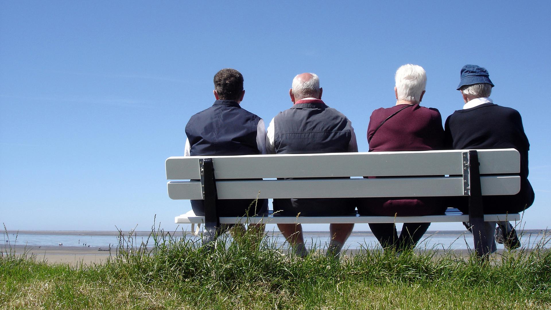 Renter Paare auf einer Bank im Sommer mit Meer im Hintergrund | Photocase/madochab