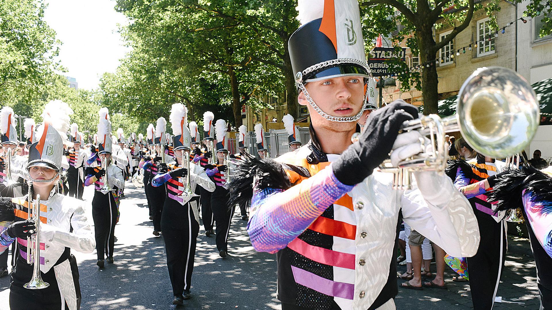Teilnehmer in Trachten und Kostümen gehen während des Schützenausmarsches durch die Innenstadt und machen Musik. | NDR, Julius Matuschik