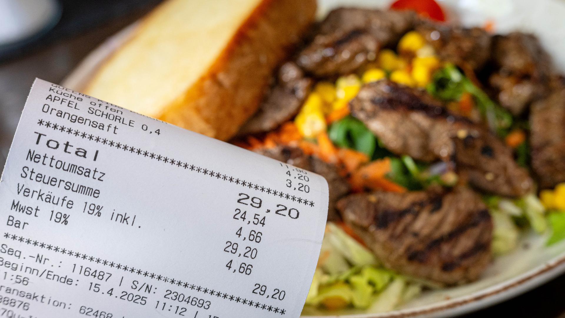 Eine Rechnung neben einem vollen Teller in einem Restaurants.  | picture alliance/dpa/Sina Schuldt