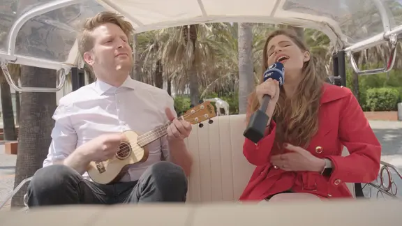 Laura Rizotto sitzt im Tuk Tuk und singt, Moderator Stefan Spiegel spielt dazu Ukulele.